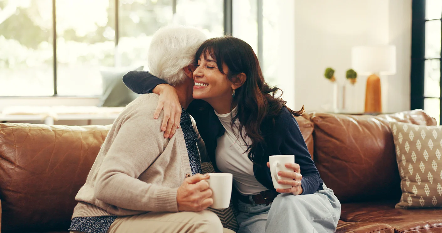 Daughter comforting stressed senior mother on sofa at home, illustrating caregiver burnout in Spokane Valley