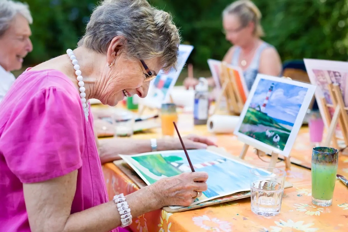 Senior woman smiling and drawing with a group during an assisted living activity calendar program