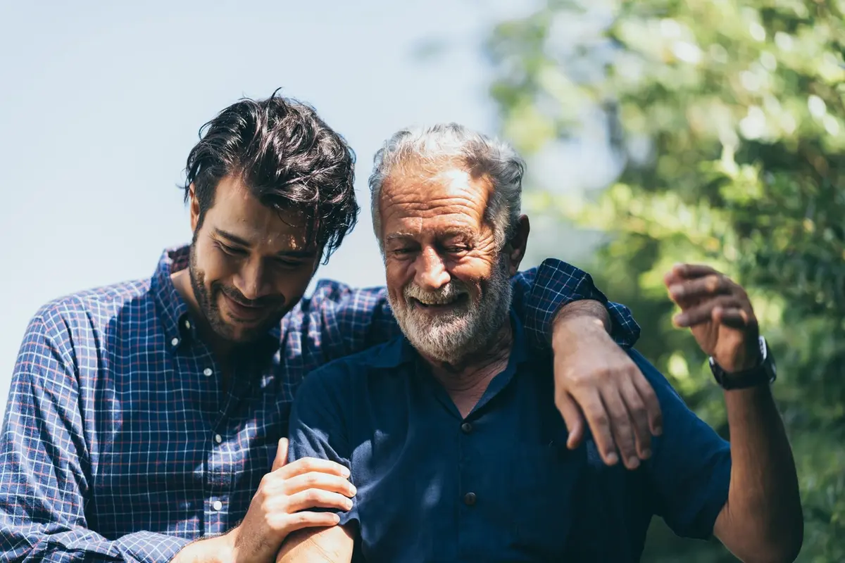 Young family caregiver smiling despite caregiver exhaustion while supporting an aging loved one.
