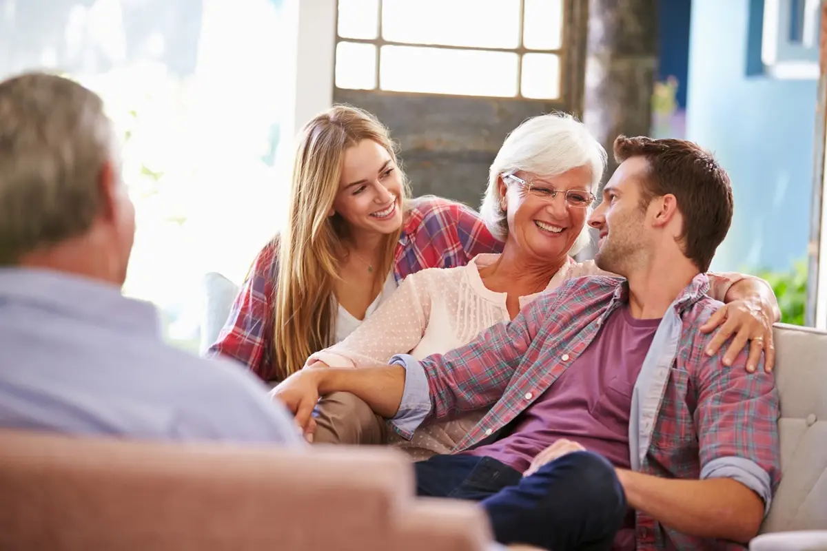 Adult children relaxing with their senior parent on a sofa during a family conversation about when your parent refuses help.